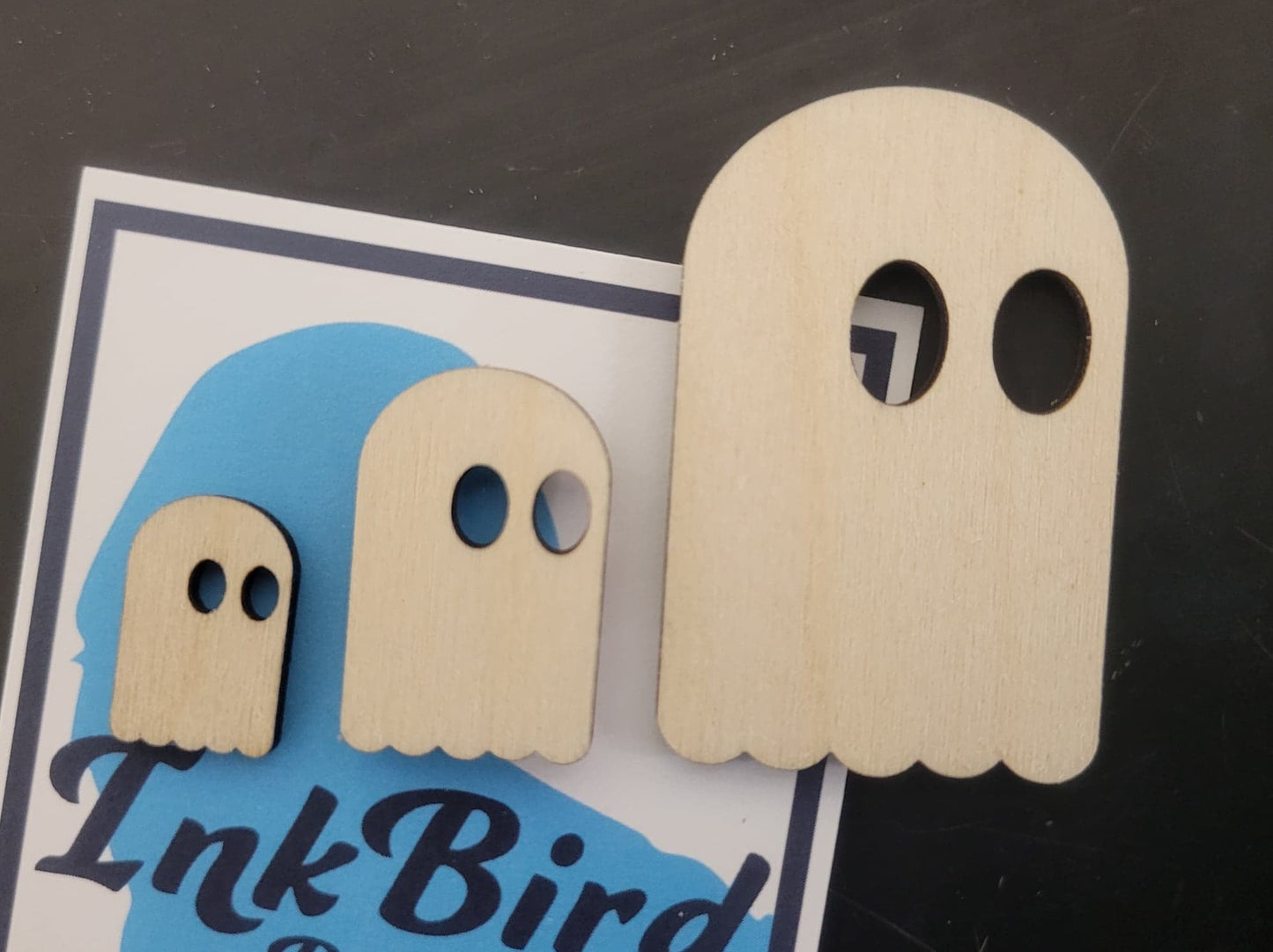 Set of three laser-cut birch wood ghost pins in small, medium, and large sizes with oval eyes, displayed on an InkBird card.