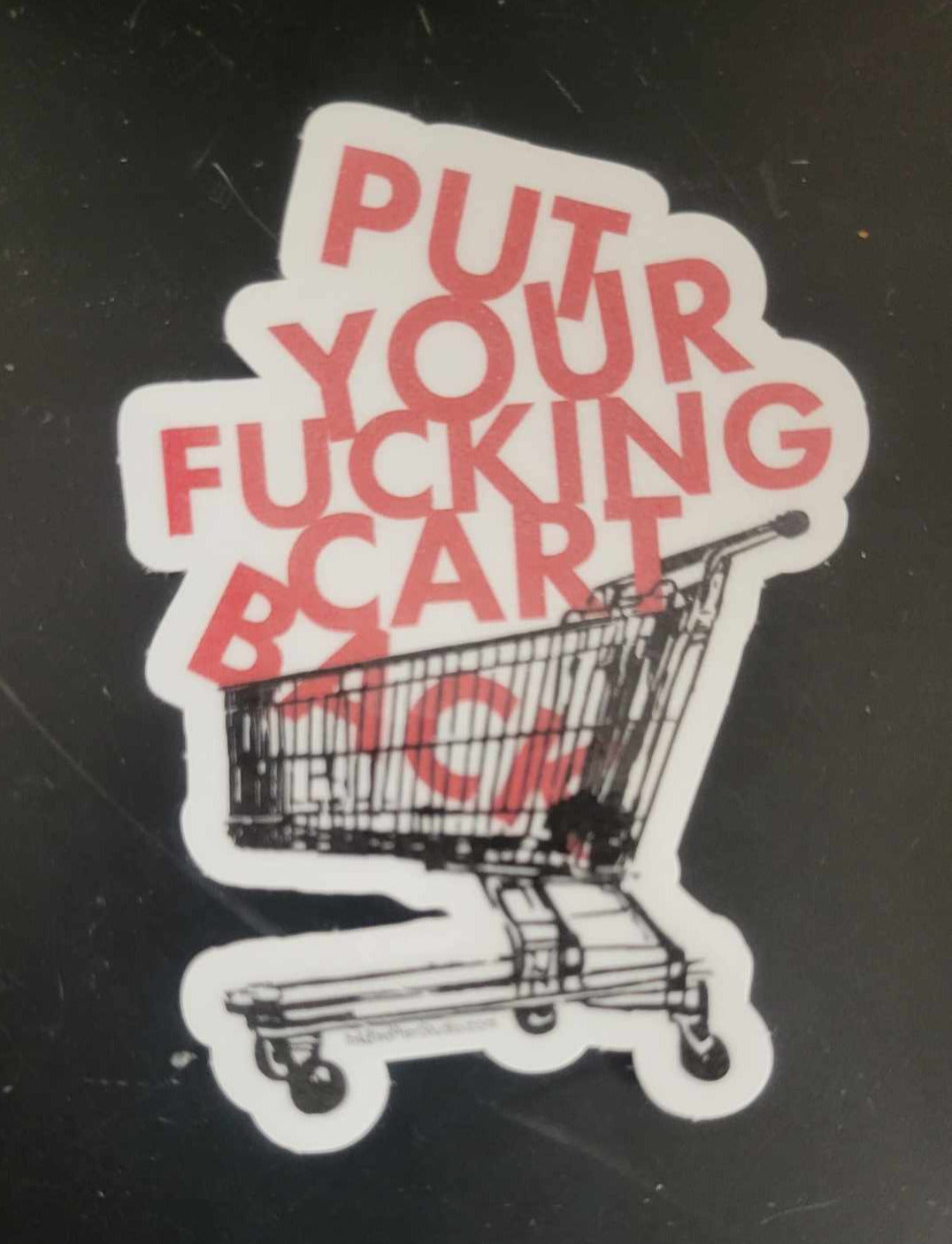 Vinyl sticker with bold red Put Your Fucking Cart Back text on black, rectangular shape; durable adhesive, perfect for laptops.