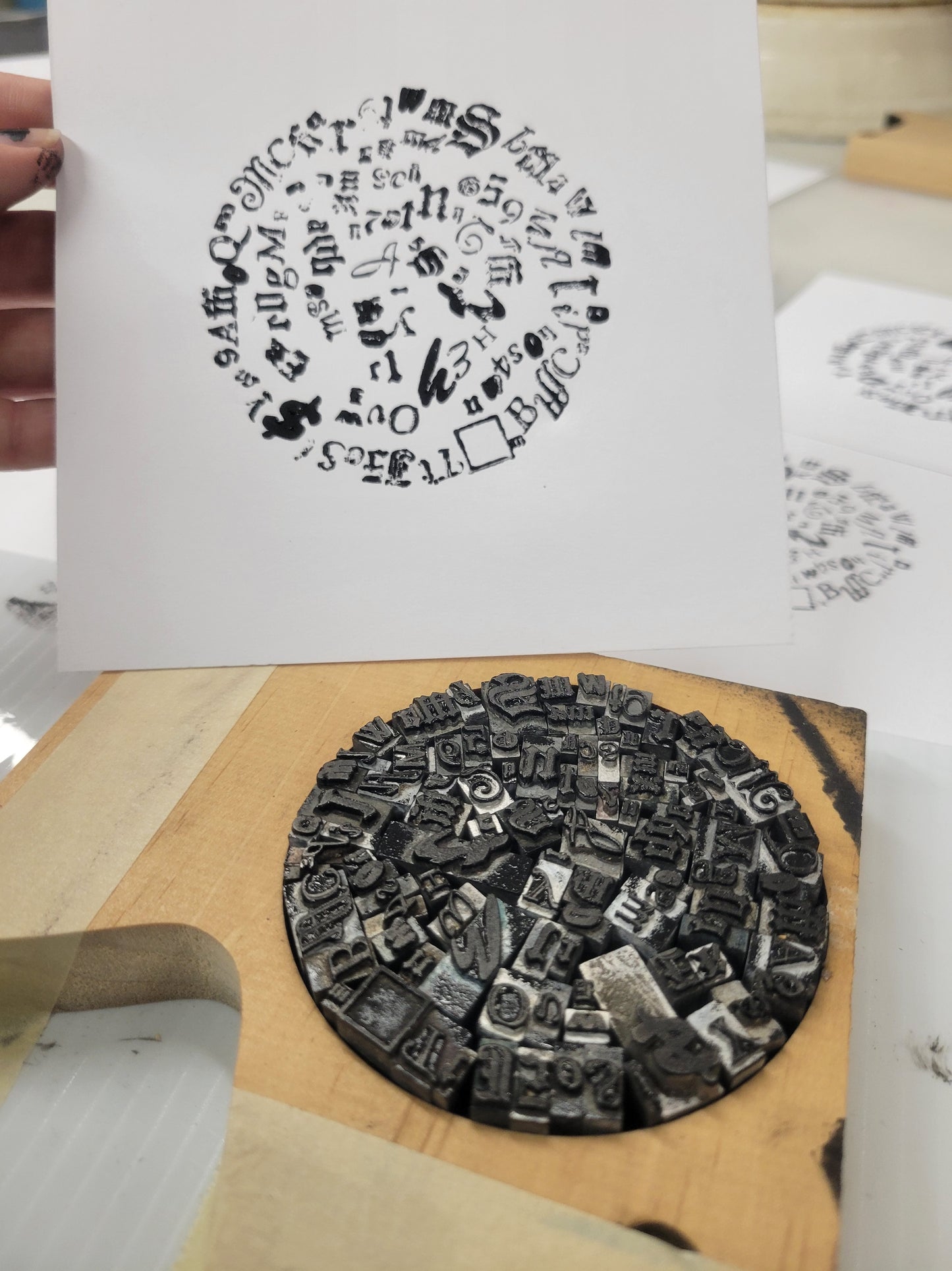 Limited run Letterpress Circle print by Claire Davis, black and white circular design of metal type in wood frame, hand-held.