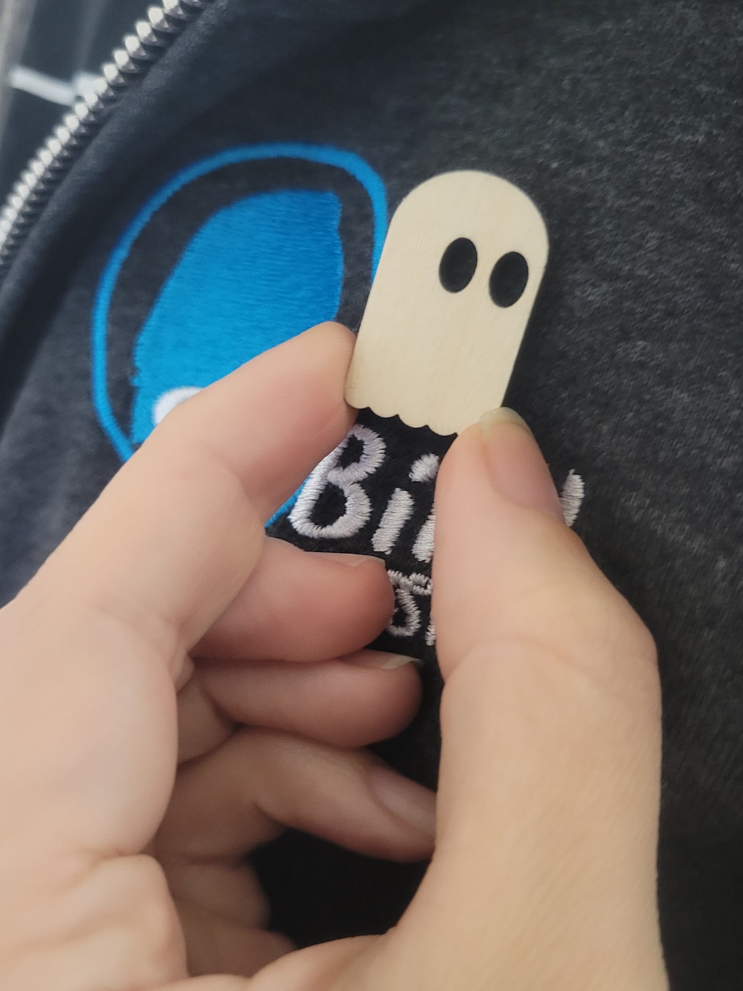 Birch wood Simple Ghost Pin with black eyes by InkBird Print Studio, shown on a dark blue and white embroidered shirt.