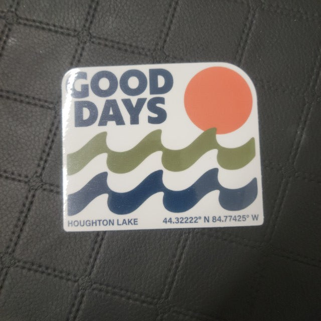 Vinyl die cut GOOD DAYS sticker with blue-green wavy text, orange sun, Houghton Lake GPS, on black quilt pattern. Printed for Good Days Marina