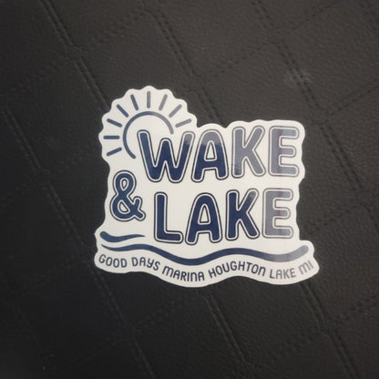 Die cut sticker on textured black premium vinyl features a sun, waves, WAKE & LAKE, and GOOD DAYS MARINA HOUGHTON LAKE MI text. Printed for Good Days Marina