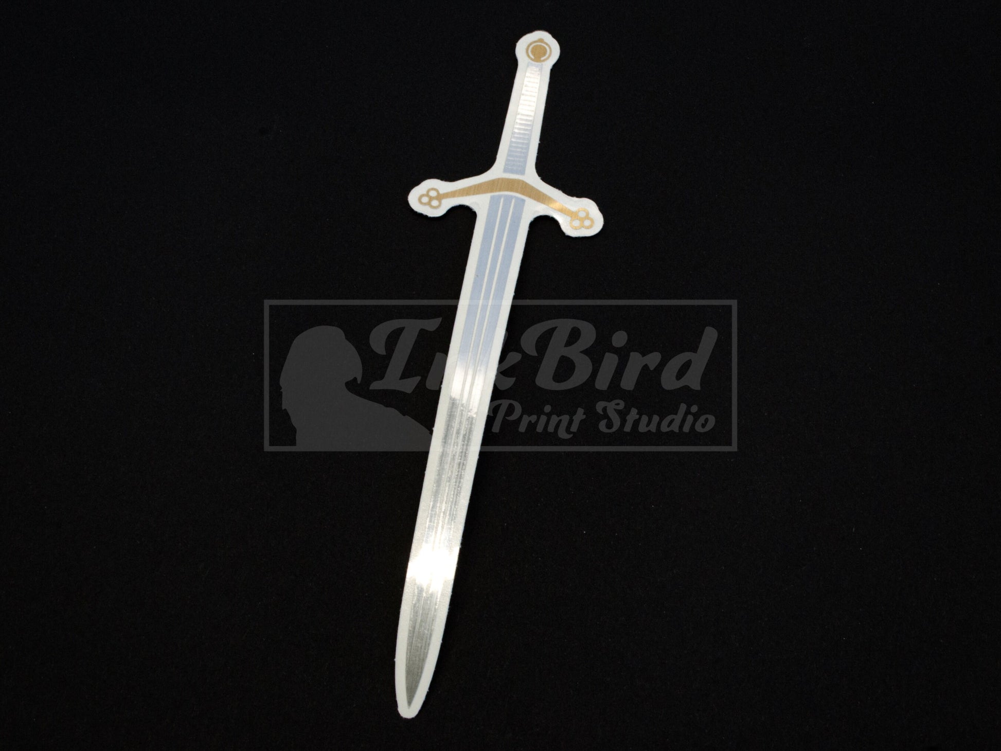 Vinyl sticker of a Scottish Claymore sword in silver and gold foil on black; durable adhesive, medieval-inspired, unique detailing.